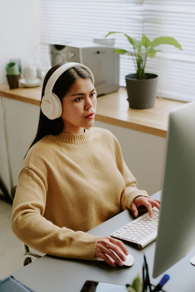 A woman listening to binaural beats while working on a computer